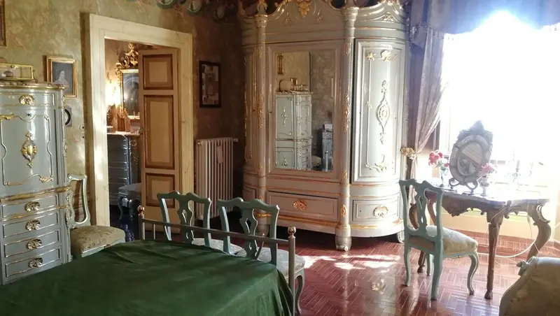 La Suite Baldacchino: il letto con la coperta verde sotto il baldacchino, fra mobili d'epoca laccati