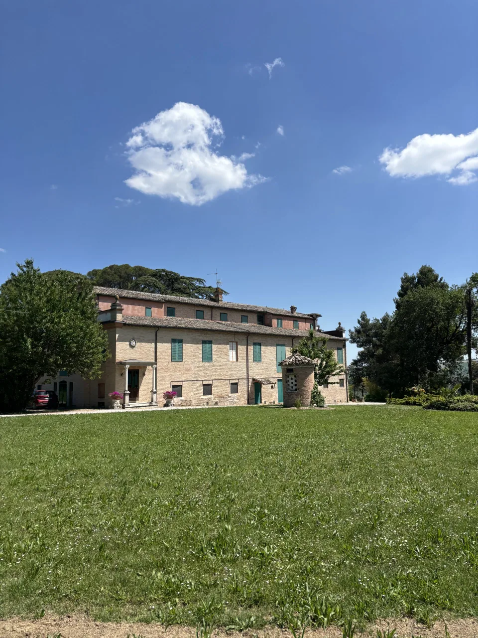 Prospetto della dimora settecentesca di Villa Luzi in mattoni e pietra con persiane verdi, su un ampio prato all'inglese