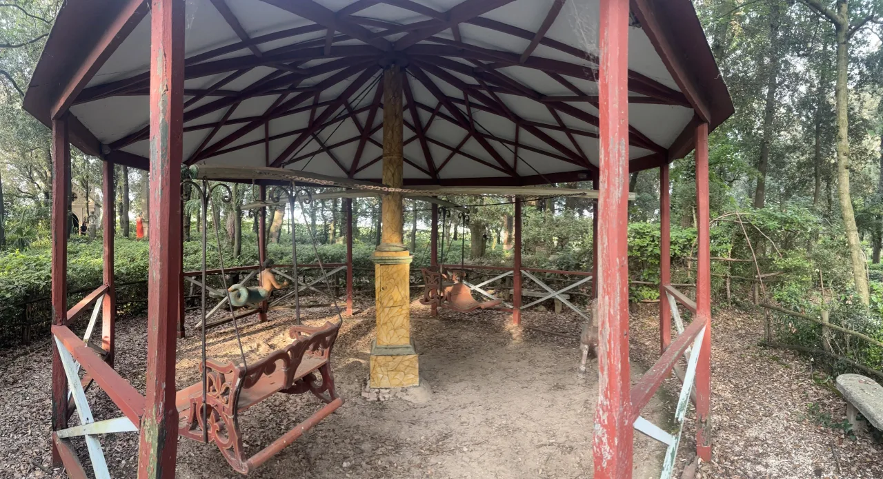 L'ingresso monumentale del parco con i due pilastri in cotto sormontati da aquile in pietra e il cancello in ferro che inquadra un'edicola votiva