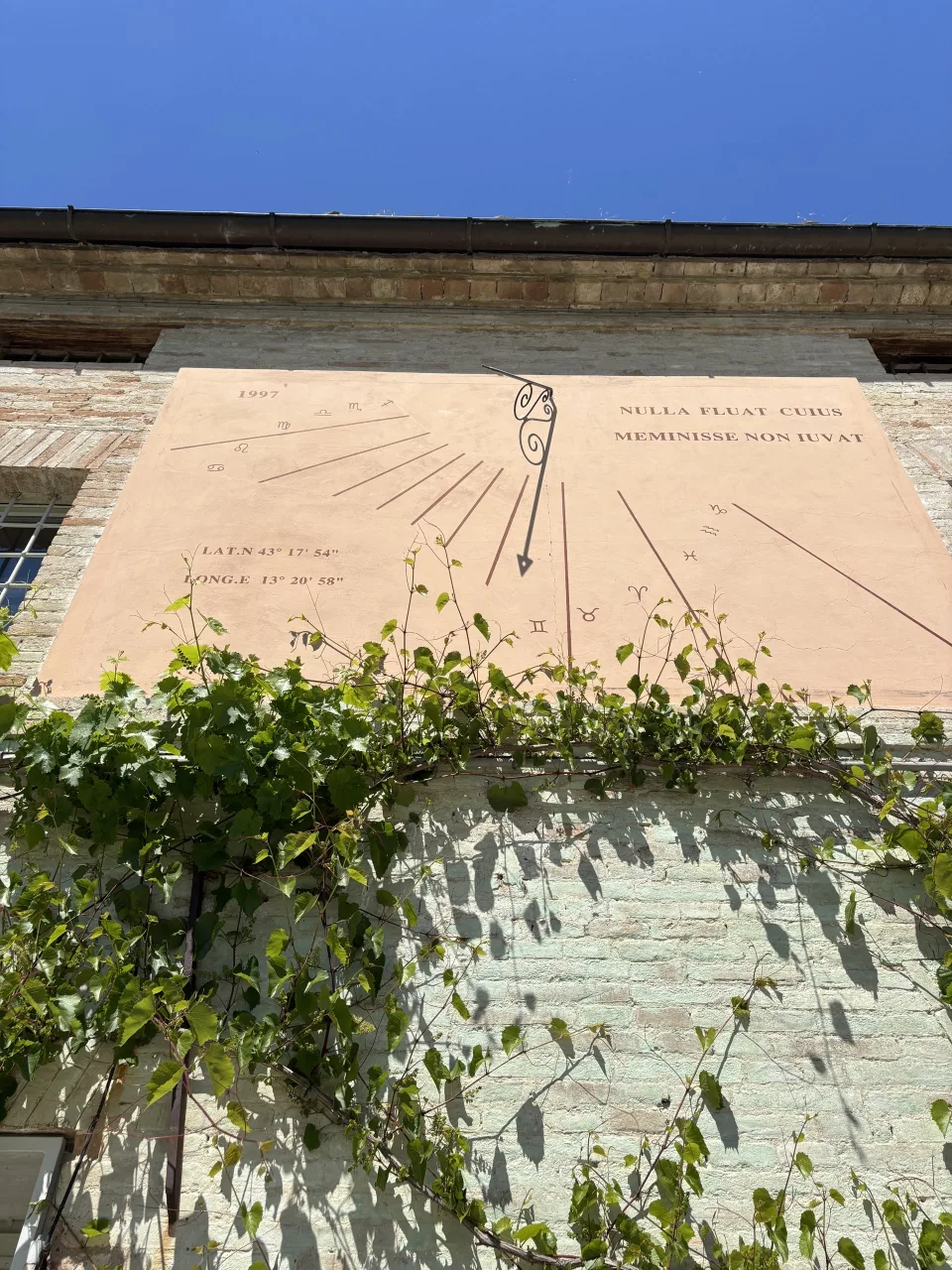 L'antica meridiana del 1997 sulla facciata di Villa Luzi, incorniciata dai tralci di vite, con il motto latino Nulla fluat cuius meminisse non iuvat