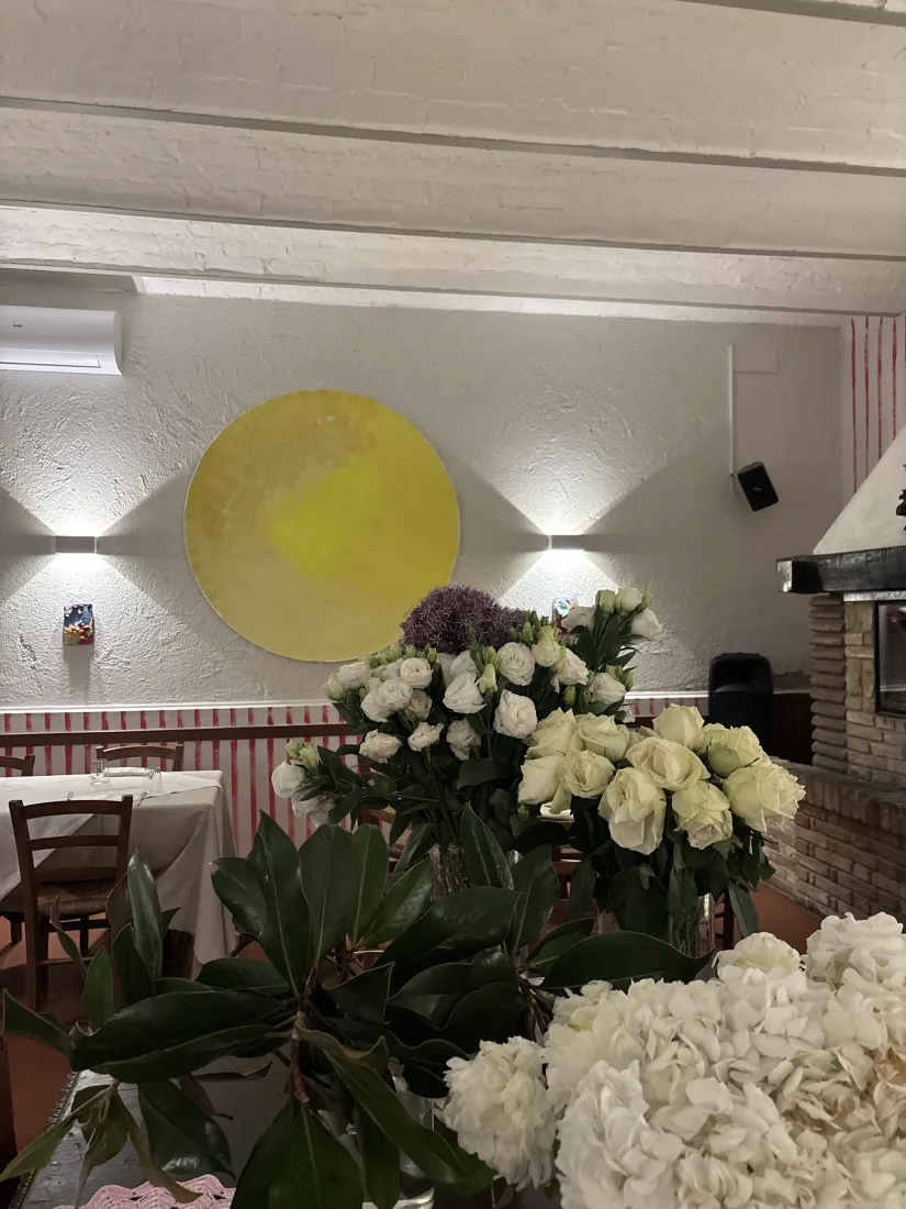 Disco dorato illuminato sulla parete avorio incorniciato da composizioni di rose bianche e ortensie