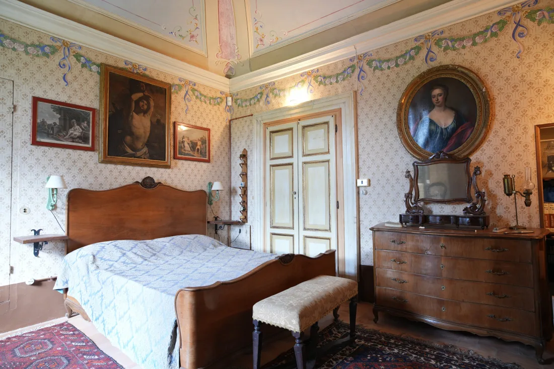 Dettaglio di parete e arredo della dimora, fra parati decorati e mobili d'epoca